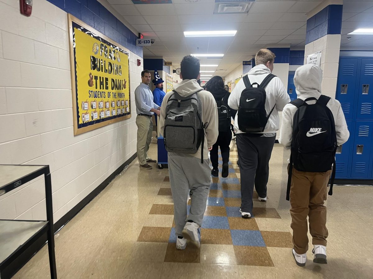 Students walk to the tardy post to receive passes to class